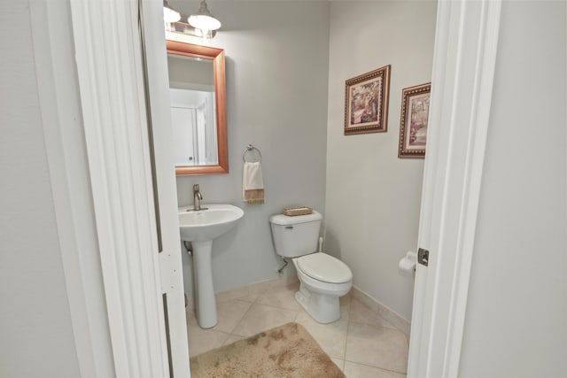 half bath featuring baseboards, tile patterned flooring, and toilet