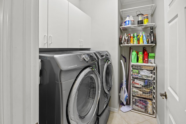 clothes washing area featuring cabinet space, light tile patterned floors, baseboards, and washer and clothes dryer