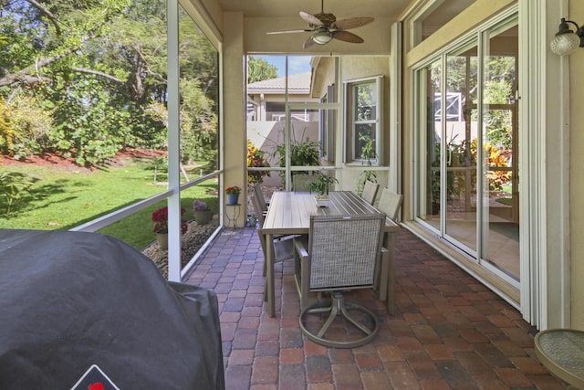 sunroom / solarium with outdoor dining area and a ceiling fan