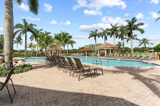 community pool with a gazebo, fence, and a patio area
