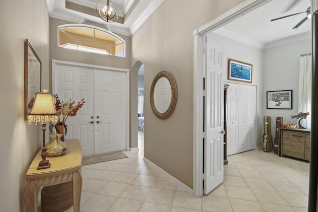 foyer entrance with crown molding, arched walkways, ceiling fan with notable chandelier, and light tile patterned flooring