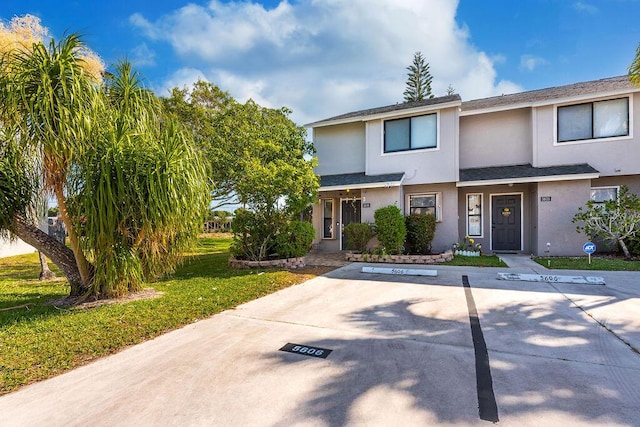 5606 Channel Dr, Lake Worth, FL 33463 - view of property with a front lawn, stucco siding, uncovered parking, and roof with shingles
