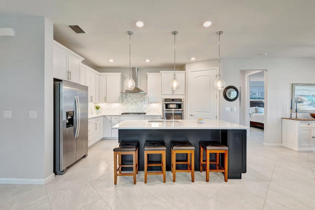 kitchen with wall chimney range hood, appliances with stainless steel finishes, light countertops, backsplash, and visible vents