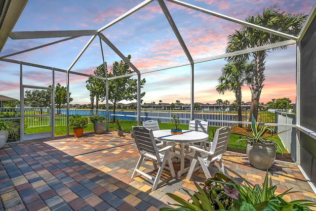 view of patio / terrace with outdoor dining area, a water view, glass enclosure, and fence