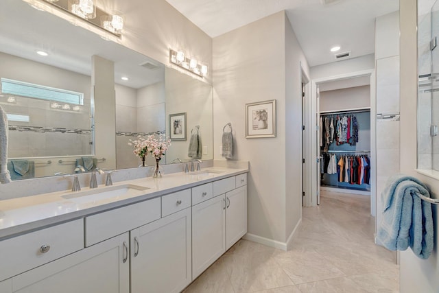 bathroom featuring a sink, a walk in shower, double vanity, and visible vents