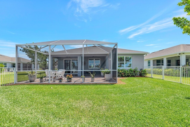 back of house with fence, stucco siding, a patio area, a lawn, and a lanai