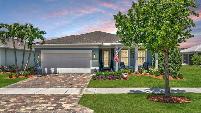 view of front of house with an attached garage, decorative driveway, stucco siding, and a yard