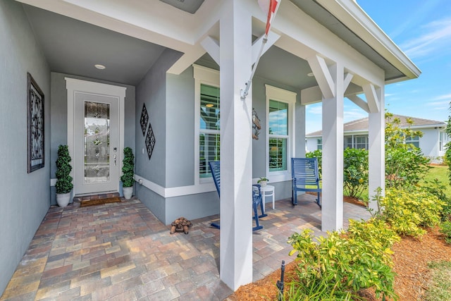 doorway to property featuring a porch and stucco siding
