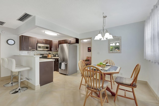 3212 NE 12th St Unit 201, Pompano Beach, FL 33062 - kitchen with visible vents, stainless steel appliances, dark brown cabinets, a peninsula, and backsplash