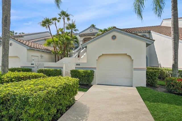 mediterranean / spanish home featuring driveway, stucco siding, fence, and a garage