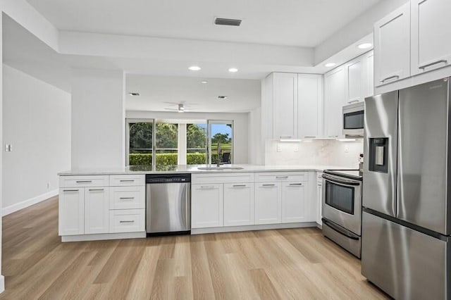 kitchen featuring appliances with stainless steel finishes, light wood finished floors, white cabinetry, recessed lighting, and light countertops