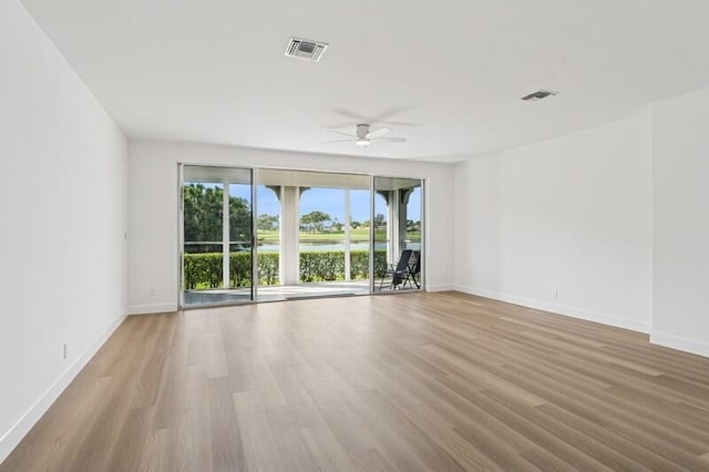 empty room with wood finished floors, a ceiling fan, and baseboards
