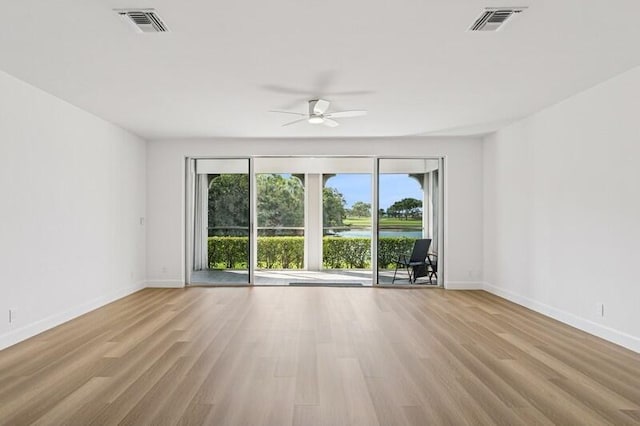 unfurnished room with healthy amount of natural light, wood finished floors, and baseboards