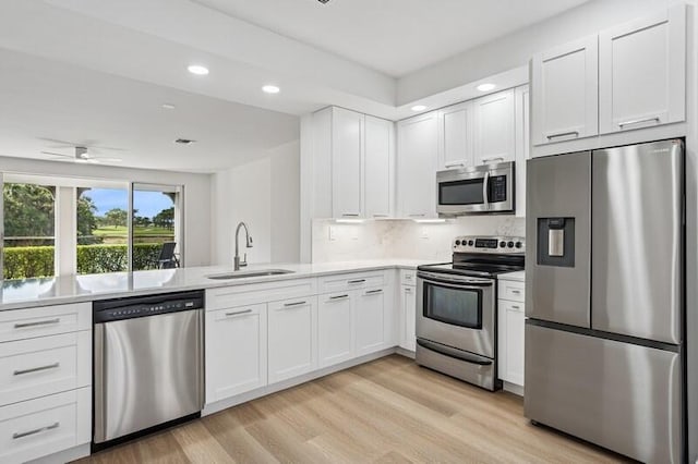 kitchen featuring appliances with stainless steel finishes, a sink, light countertops, white cabinets, and recessed lighting