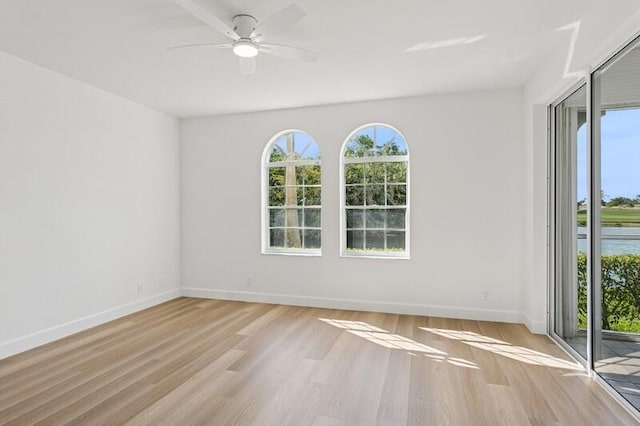 unfurnished room with plenty of natural light, wood finished floors, ceiling fan, and baseboards