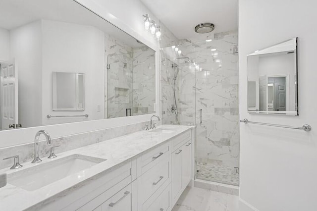 bathroom featuring marble look tile flooring, a marble finish shower, double vanity, and baseboards