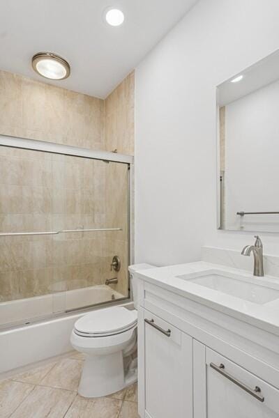bathroom featuring toilet, combined bath / shower with glass door, and vanity