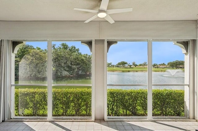 unfurnished sunroom featuring tile patterned floors, a water view, plenty of natural light, and a textured ceiling