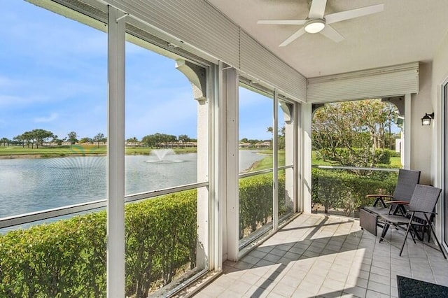 unfurnished sunroom featuring a water view, tile patterned flooring, ceiling fan, and plenty of natural light