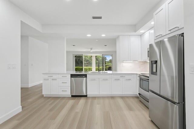 kitchen with stainless steel appliances, white cabinets, light wood-style flooring, baseboards, and a sink