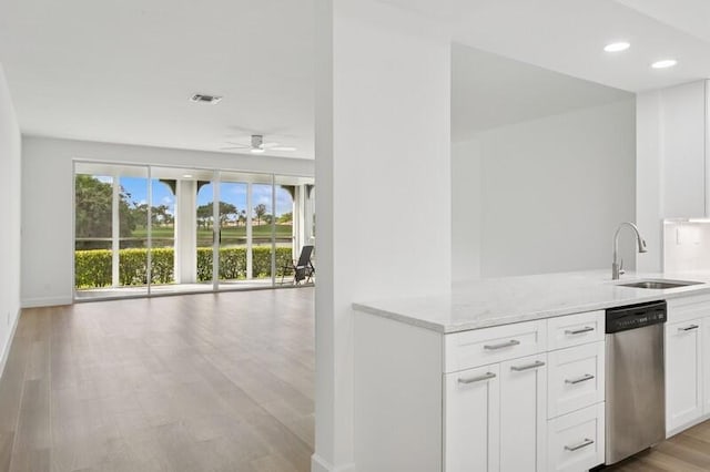 kitchen featuring a sink, stainless steel dishwasher, ceiling fan, light wood-type flooring, and light stone countertops