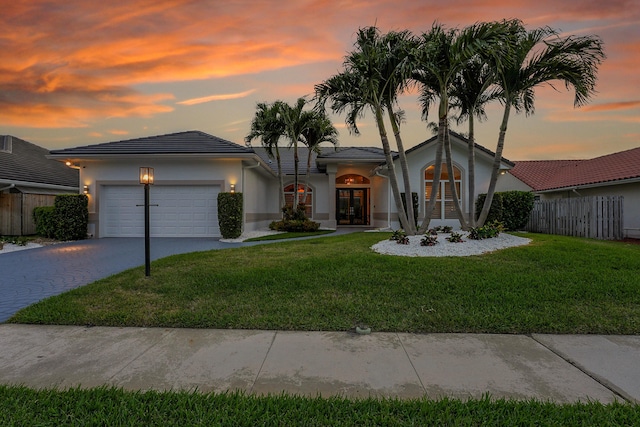 view of front facade featuring french doors, an attached garage, driveway, stucco siding, and a tiled roof