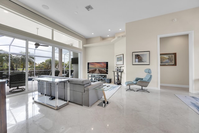 living room featuring light marble finish floors, baseboards, a high ceiling, recessed lighting, and a sunroom