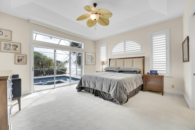 bedroom featuring light colored carpet, access to exterior, baseboards, a tray ceiling, and a ceiling fan