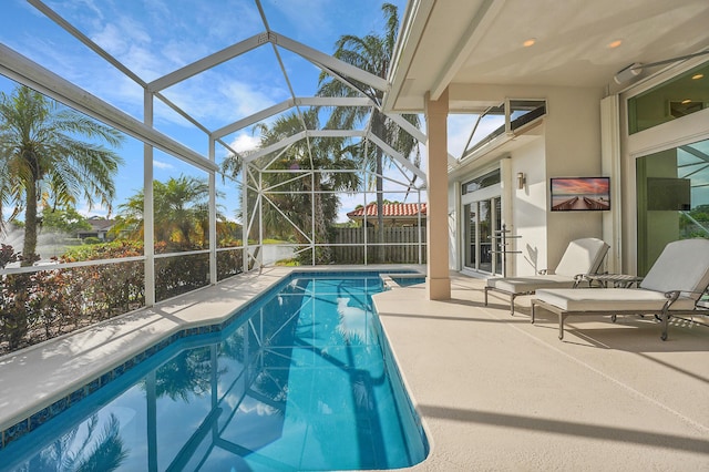 swimming pool featuring a patio area, glass enclosure, and fence