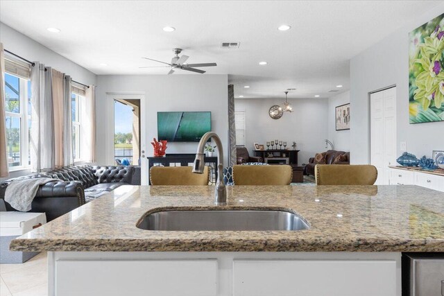 11400 SW Reston Ct, Port Saint Lucie, FL 34987 - kitchen with open floor plan, light stone counters, white cabinetry, and recessed lighting