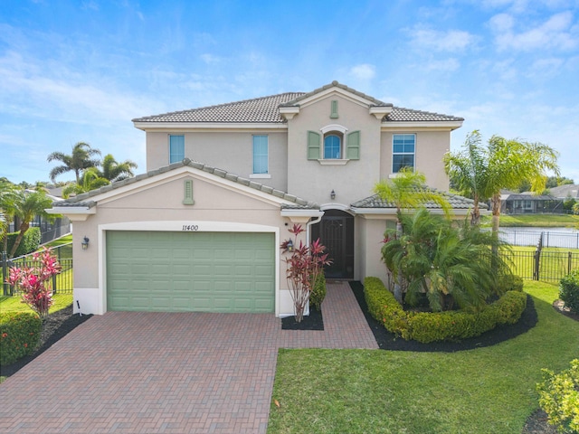 mediterranean / spanish house featuring stucco siding, a tile roof, decorative driveway, and a garage