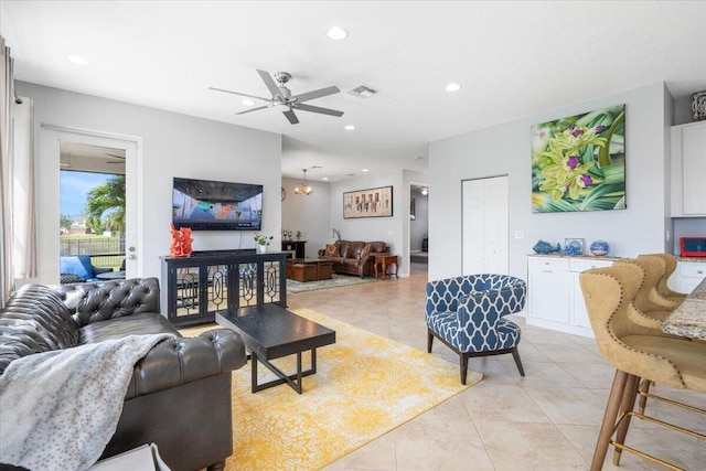 living area with light tile patterned floors, recessed lighting, a ceiling fan, and a chandelier