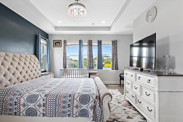 bedroom with a chandelier, a raised ceiling, light wood-type flooring, baseboards, and recessed lighting
