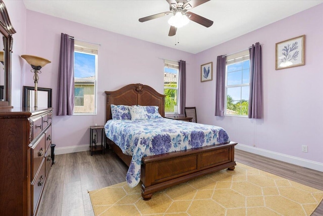 bedroom with light wood-style flooring, baseboards, and ceiling fan