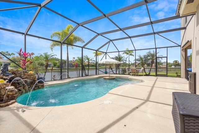 outdoor pool with a patio, a water view, and glass enclosure