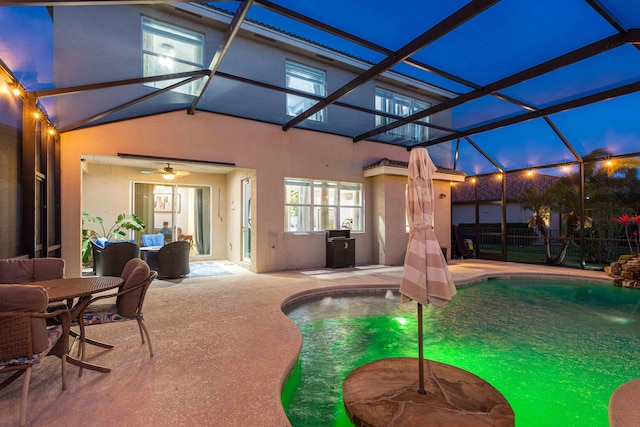 view of swimming pool with a patio area, glass enclosure, fence, and a ceiling fan