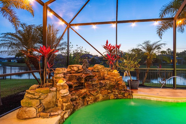 view of pool with fence, a lanai, and a water view