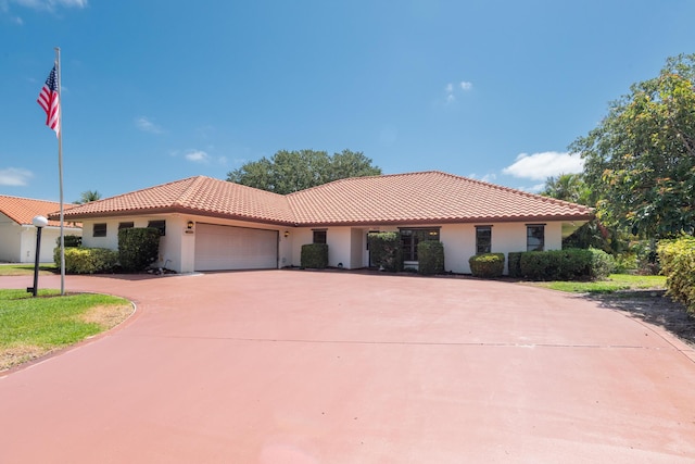 3984 SE Fairway E, Stuart, FL 34997 - mediterranean / spanish home featuring curved driveway, a garage, stucco siding, and a tile roof