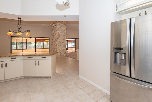 3984 SE Fairway E, Stuart, FL 34997 - kitchen featuring white cabinets, light stone counters, stainless steel fridge, a ceiling fan, and decorative light fixtures