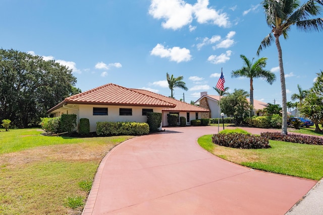 3984 SE Fairway E, Stuart, FL 34997 - view of front facade featuring stucco siding, curved driveway, a tile roof, and a front lawn