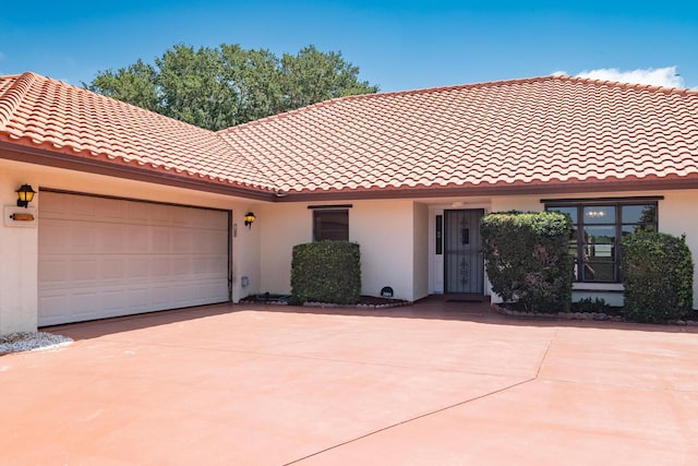 3984 SE Fairway E, Stuart, FL 34997 - view of front of property featuring a tiled roof, an attached garage, concrete driveway, and stucco siding