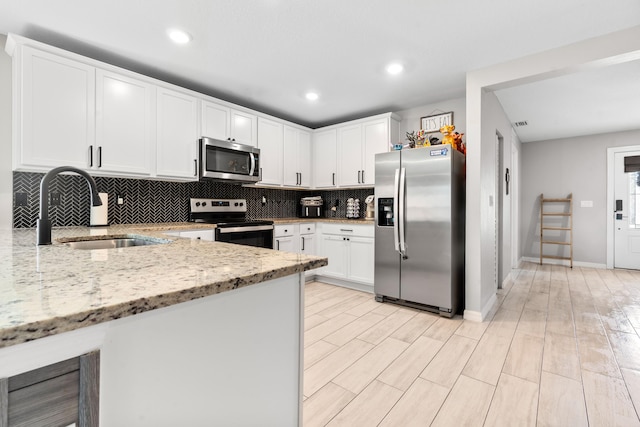 885 SW Squirrel Ave, Port Saint Lucie, FL 34953 - kitchen featuring stainless steel appliances, a sink, backsplash, light stone counters, and white cabinets