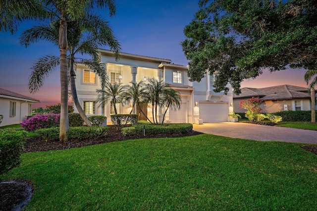 mediterranean / spanish-style home with a front lawn, stucco siding, a tile roof, driveway, and a garage