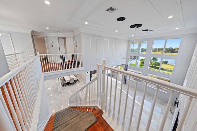 staircase featuring recessed lighting, visible vents, ornamental molding, and a water view