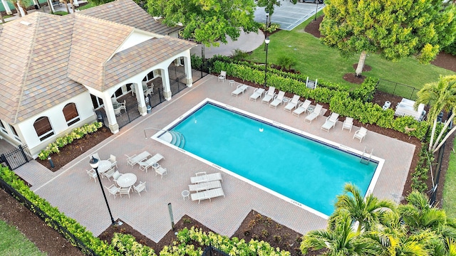 community pool with a yard, fence, and a patio area