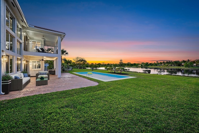 view of swimming pool featuring an outdoor hangout area, a yard, a water view, ceiling fan, and a patio