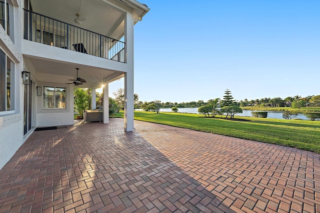 view of patio featuring a ceiling fan, a balcony, and a water view