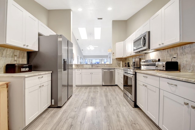 2406 Landings Blvd, Greenacres, FL 33413 - kitchen featuring stainless steel appliances, a skylight, white cabinetry, decorative backsplash, and recessed lighting