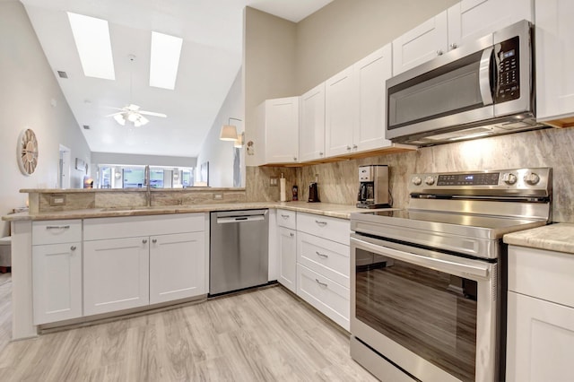 2406 Landings Blvd, Greenacres, FL 33413 - kitchen with stainless steel appliances, a skylight, a sink, lofted ceiling, and backsplash