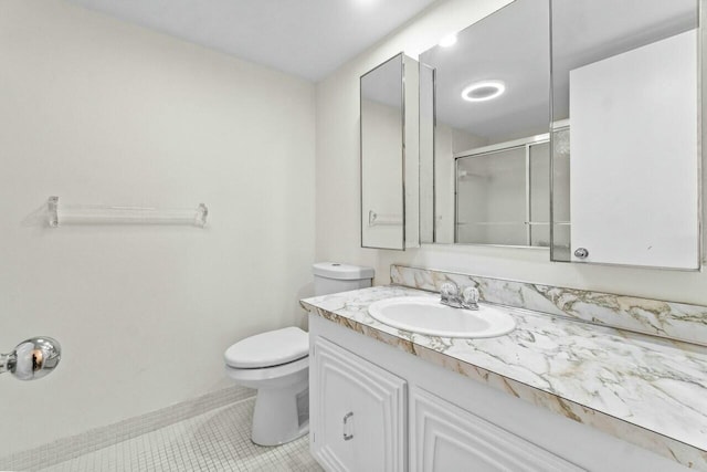 bathroom with a shower stall, baseboards, toilet, vanity, and tile patterned flooring